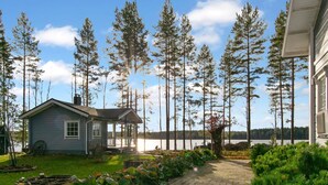 A house with a porch, a pathway, and a view of a lake surrounded by trees.