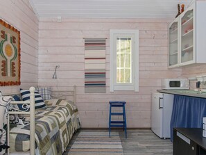 A small, cozy room with a bed, a blue stool, a microwave, and a refrigerator. - Rehviranta by Interhome (Kuopio)