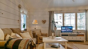 A living room with a sofa, a coffee table, a TV, and a window with curtains.