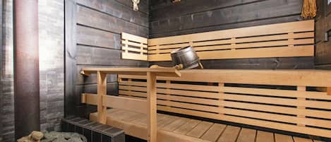 A sauna with wooden benches and a stone basin.