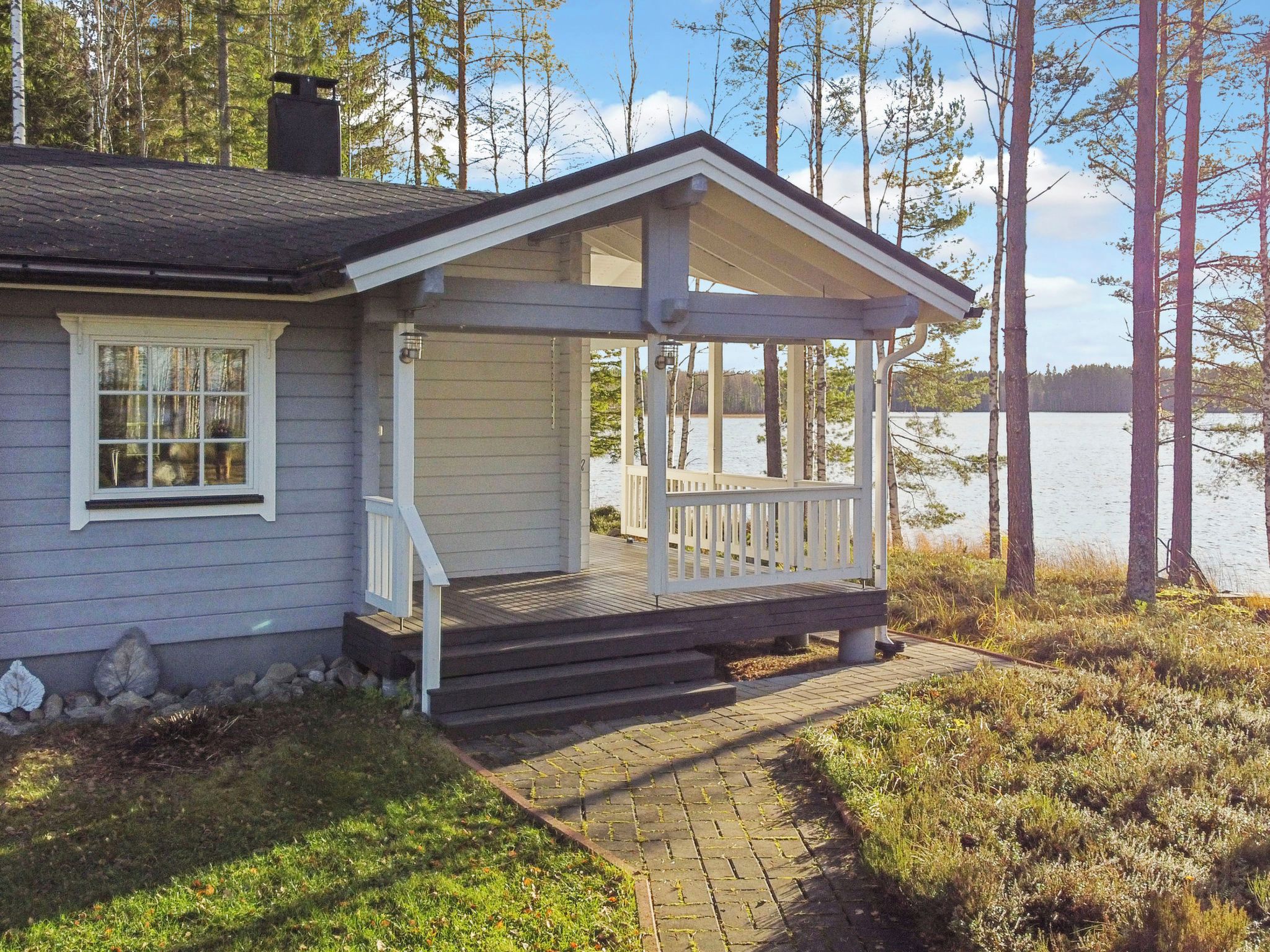 A house with a porch, steps leading to the porch, and a view of a lake.