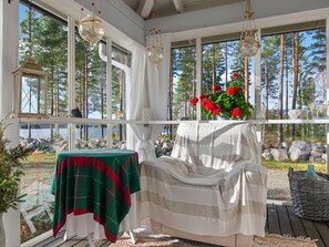 A covered porch with a table, chairs, and a view of a forest and lake. - Rehviranta by Interhome (Kuopio)