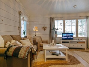 A cozy living room with a sofa, armchair, coffee table, and a television on a white cabinet. - Rehviranta by Interhome (Kuopio)