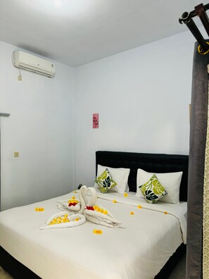 A hotel room with a neatly made bed, a black headboard, and a wall-mounted air conditioner. - Biya Lumba (Karangasem)