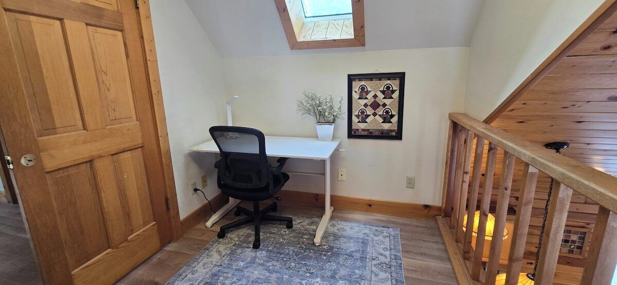 A room with a desk, chair, and a small potted plant.