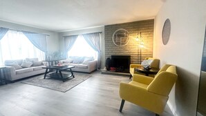 A living room with a fireplace, two sofas, a coffee table, and a yellow armchair.