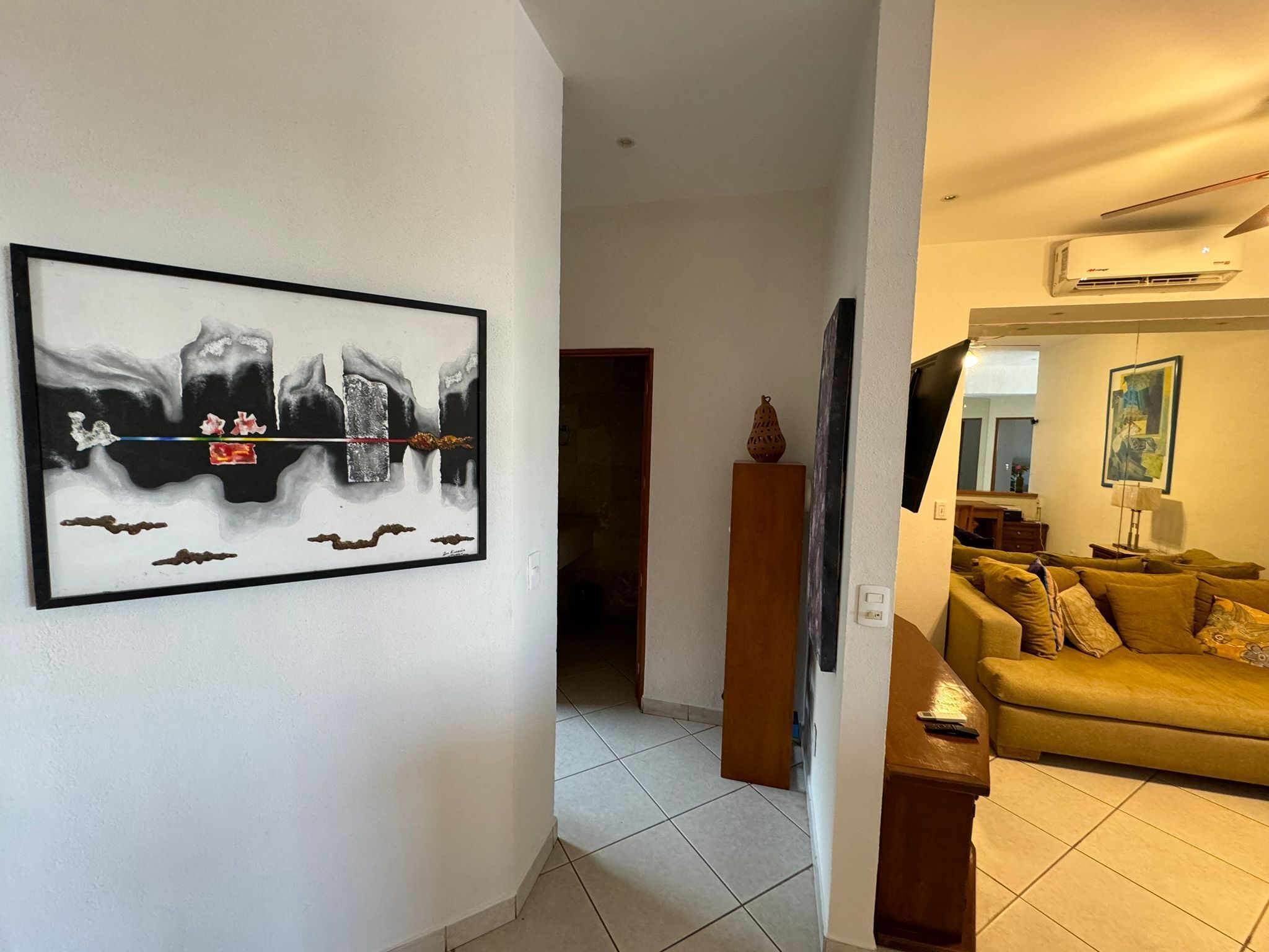 Un salon avec un grand tableau abstrait, un canapé et un téléviseur.