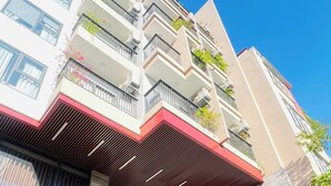 A multi-story building with balconies, a spa sign, and a sign for 'FLESTA NUI TRUC'. - FLESTA Nui Truc Serviced Apartment & Hotel (Hanoi)
