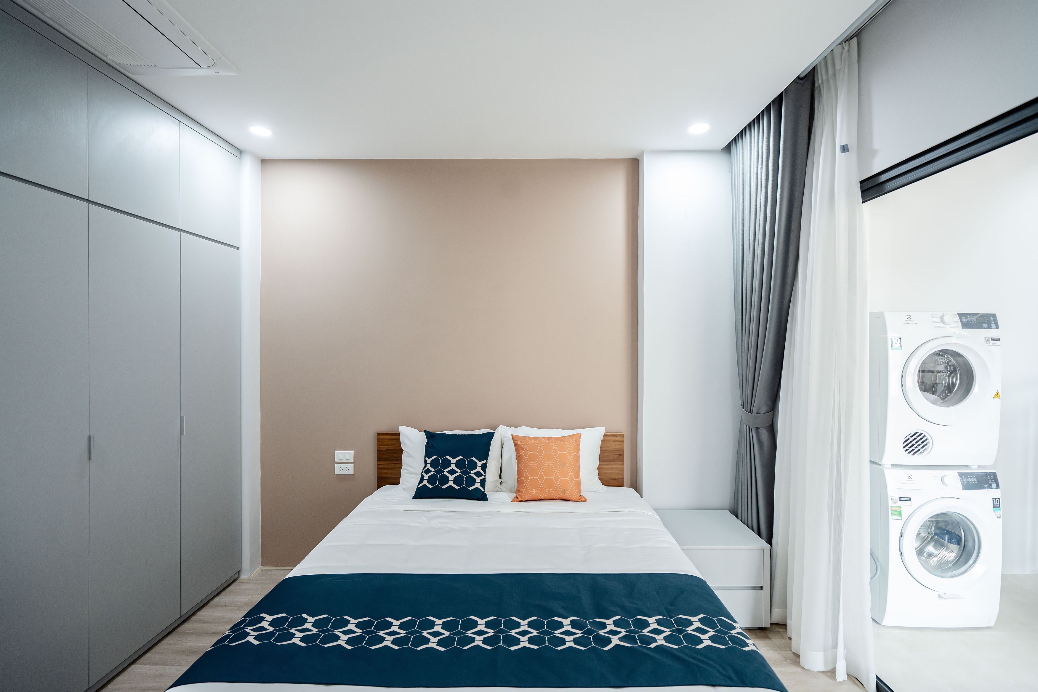 A hotel room with a bed, a washing machine, and a wardrobe.