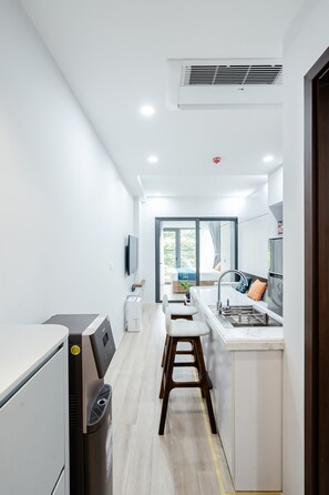 A modern kitchen with a central island, a built-in oven, and a large window. - FLESTA Nui Truc Serviced Apartment & Hotel (Hanoi)
