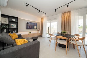 A modern living room with a grey sofa, wooden dining table, and chairs. - Smash A - Apartments with Private Heated Pool (Novalja)