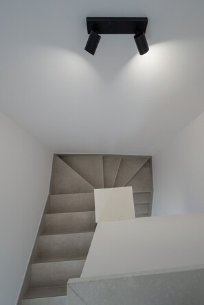 A staircase with a geometric design, leading to a landing with a light-colored wall. - Smash A - Apartments with Private Heated Pool (Novalja)