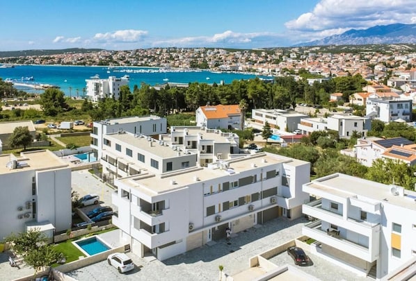 Un immeuble d’appartements moderne, doté de plusieurs étages, d’une piscine et offrant une vue sur la mer et les montagnes.