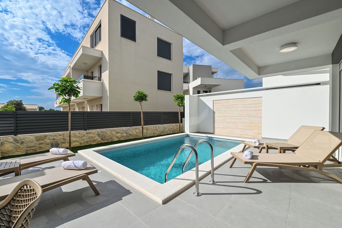 A modern outdoor pool area with lounge chairs and a clear blue pool.