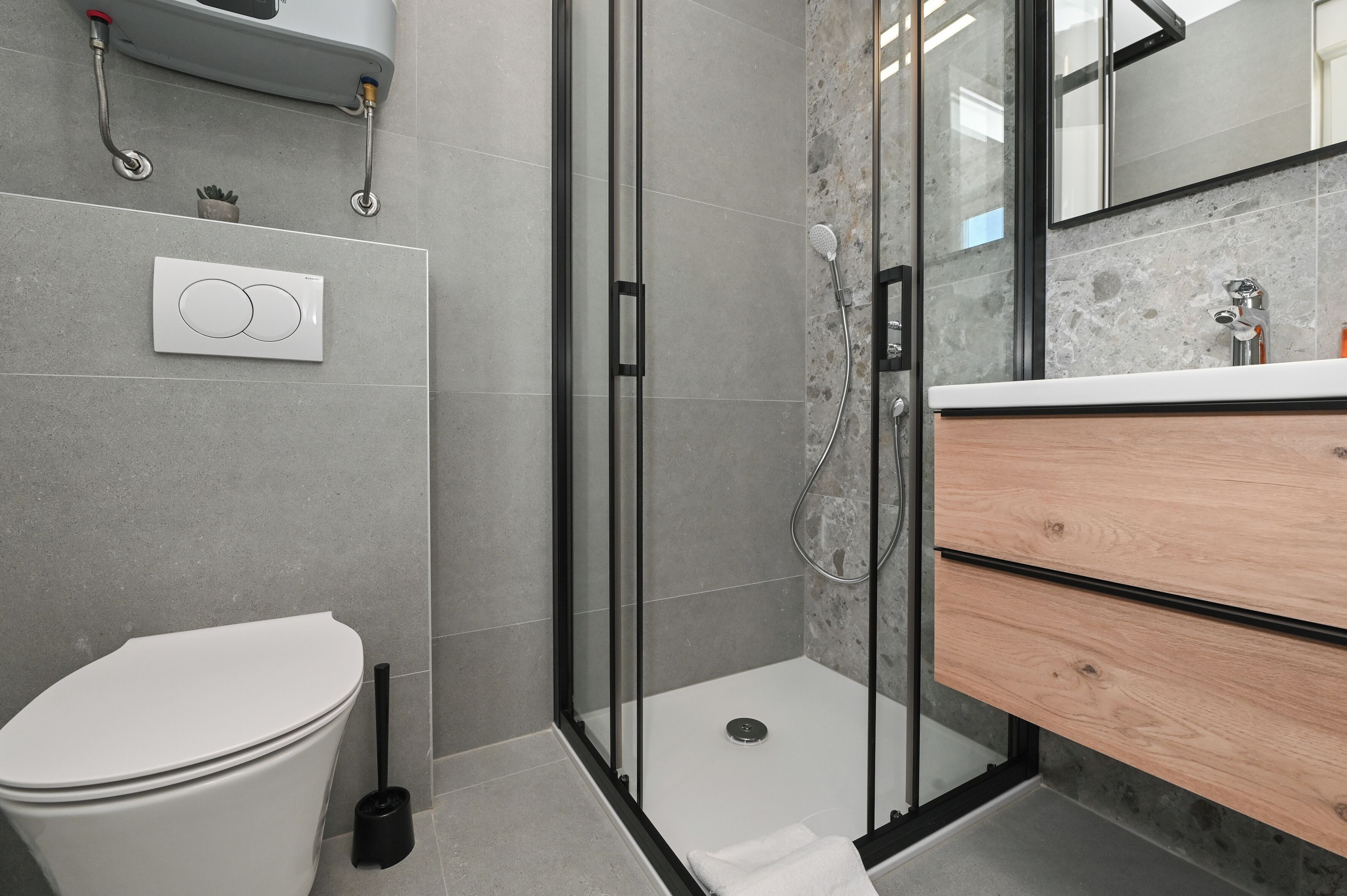 A modern bathroom with a toilet, shower, and vanity.