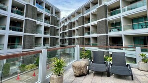 Un moderno edificio de varios pisos con balcones, plantas en macetas y mobiliario exterior.