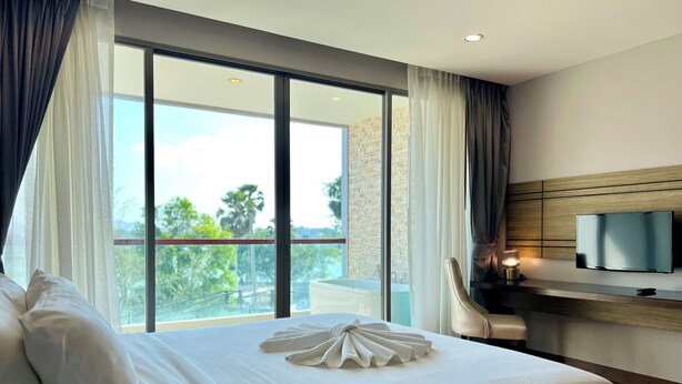 Habitación de hotel con una cama grande, un televisor de pantalla plana en la pared y vistas al exterior.
