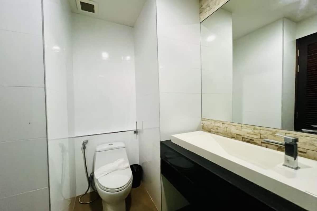 Ein modernes Badezimmer mit Toilette in Weiß, einem Waschbecken mit schwarzer Arbeitsplatte und einem Spiegel darüber.