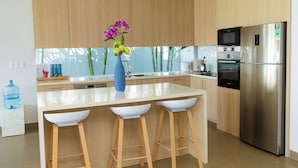Una cocina moderna con armarios de madera, un refrigerador de acero inoxidable y una isla central con taburetes de bar.
