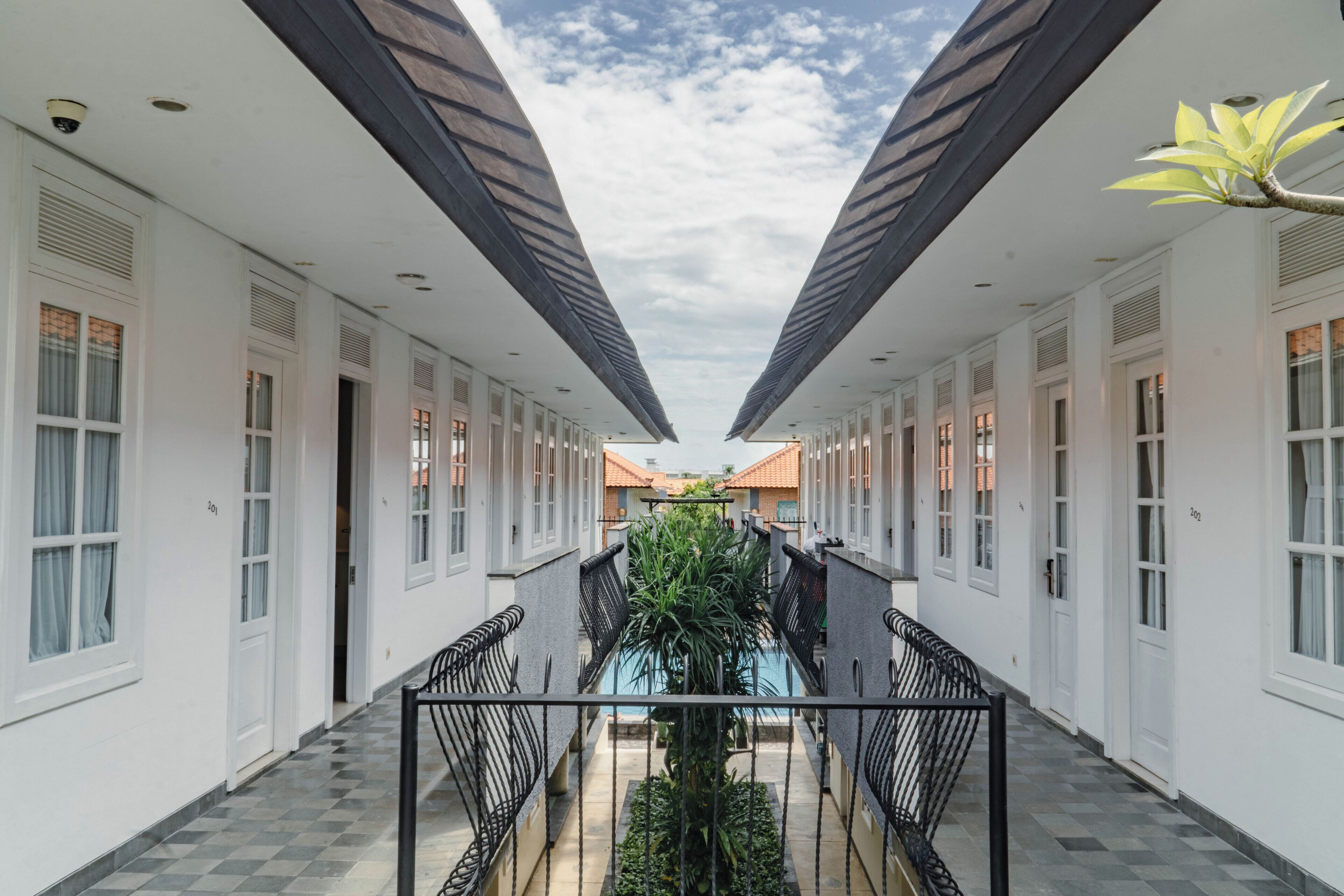A corridor with a central pool, flanked by white walls and doors numbered 201 and 202.