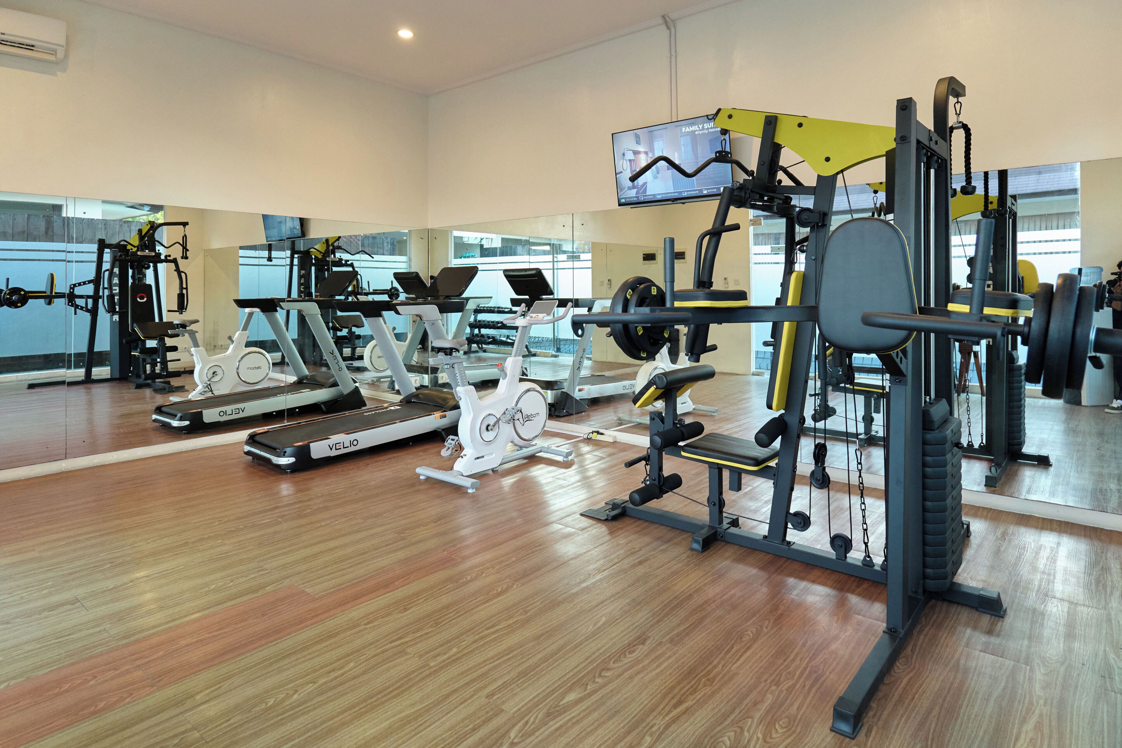 Un gimnasio con diversos equipos de ejercicio, como cintas de correr, bicicletas estáticas y máquinas de pesas.