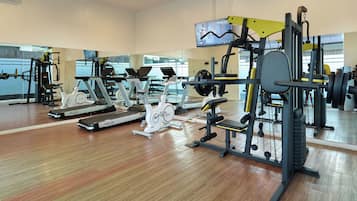 Un gimnasio con diversos equipos de ejercicio, como cintas de correr, bicicletas estáticas y máquinas de pesas.