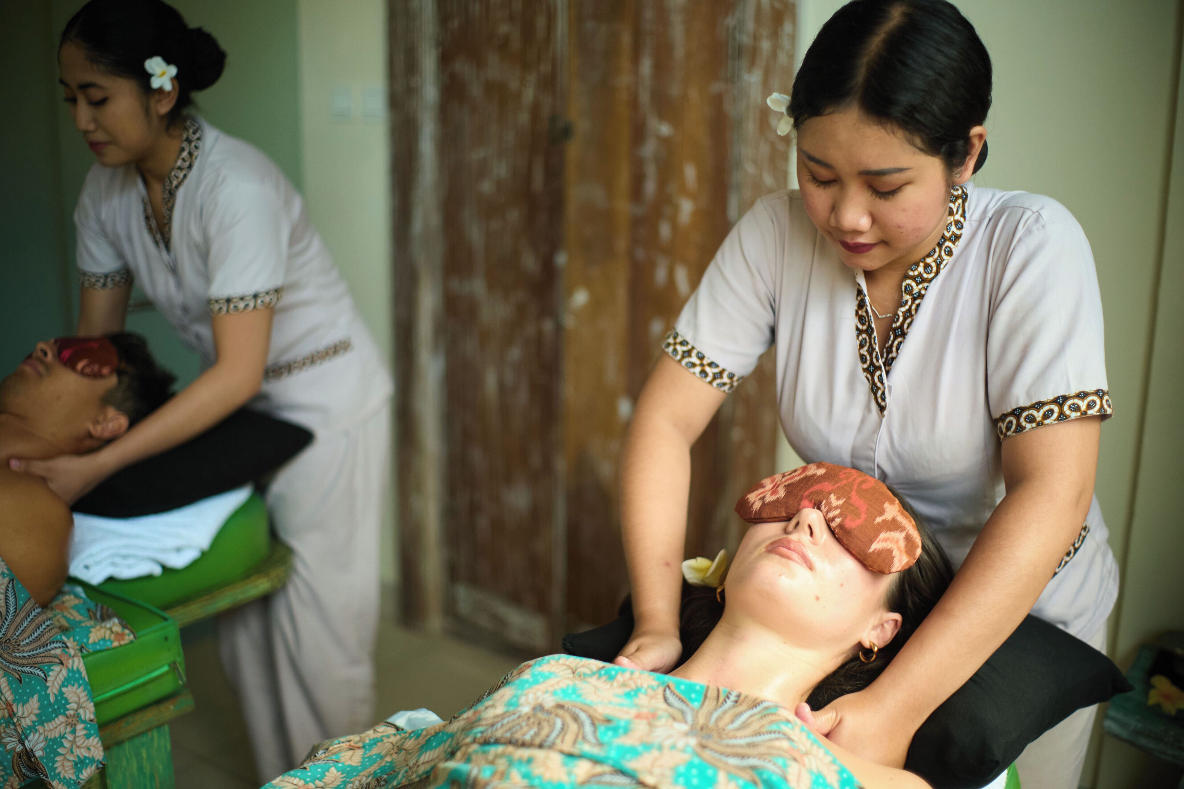 A massage therapy session in a room with a wooden door and a green massage table.