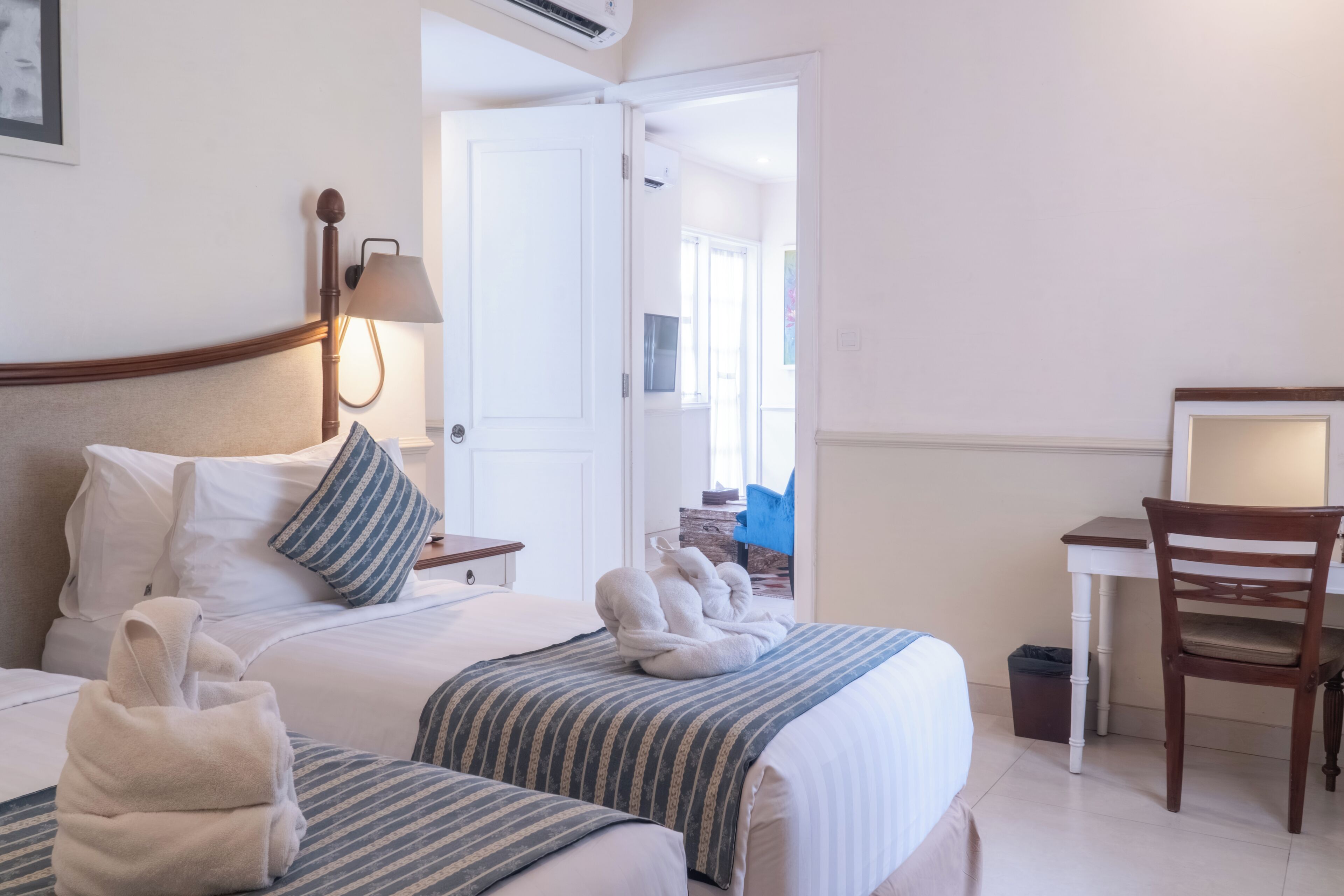 Une chambre d’hôtel avec deux lits, un bureau, une chaise, une lampe et une vue sur l’extérieur.