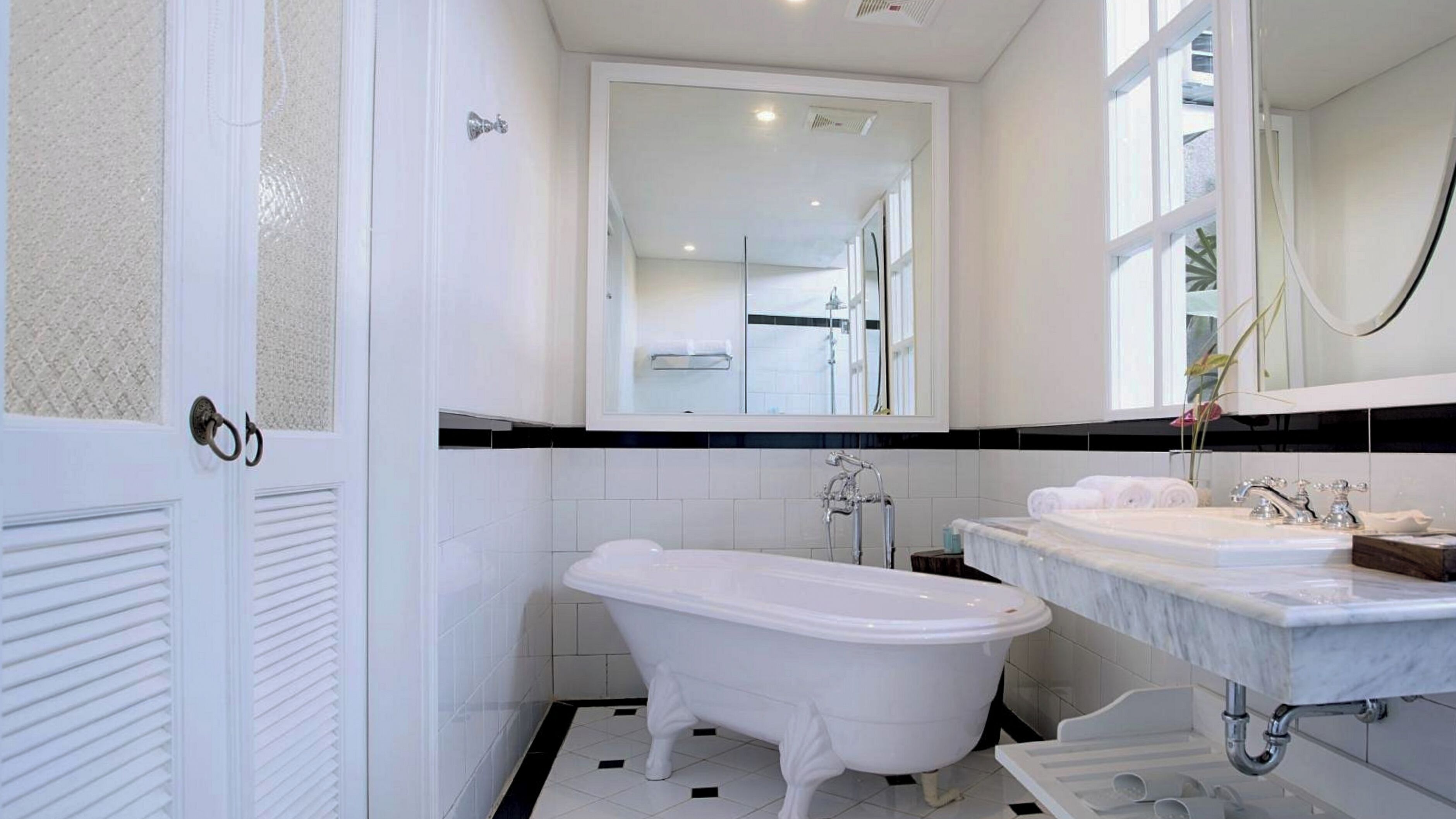Un baño con una bañera independiente, un espejo grande y un tocador con dos lavamanos.