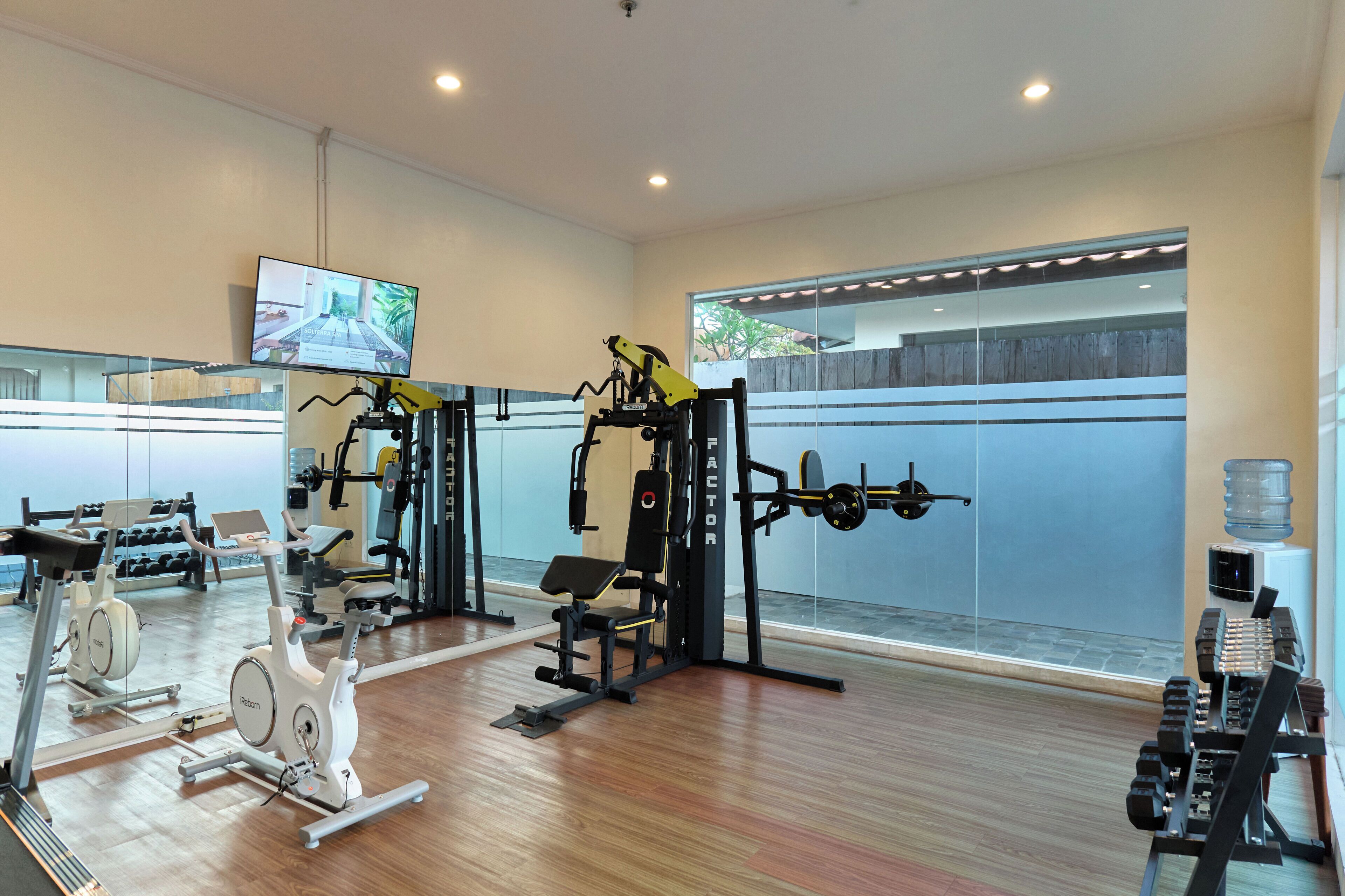 A gym with cardio equipment, weight machines, and dumbbells.