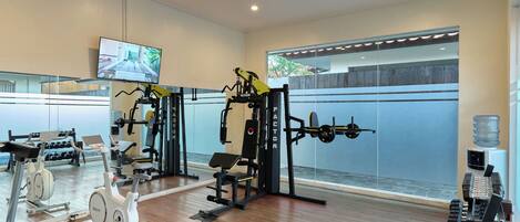 A gym with cardio equipment, weight machines, and dumbbells.