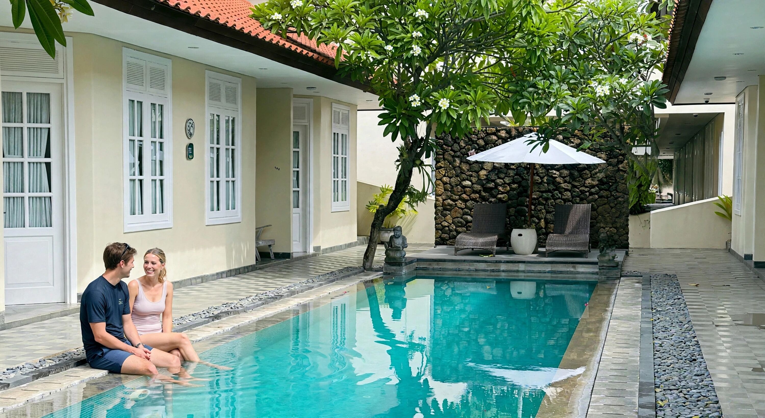 A swimming pool with a stone border, a statue, and a bench under a tree.