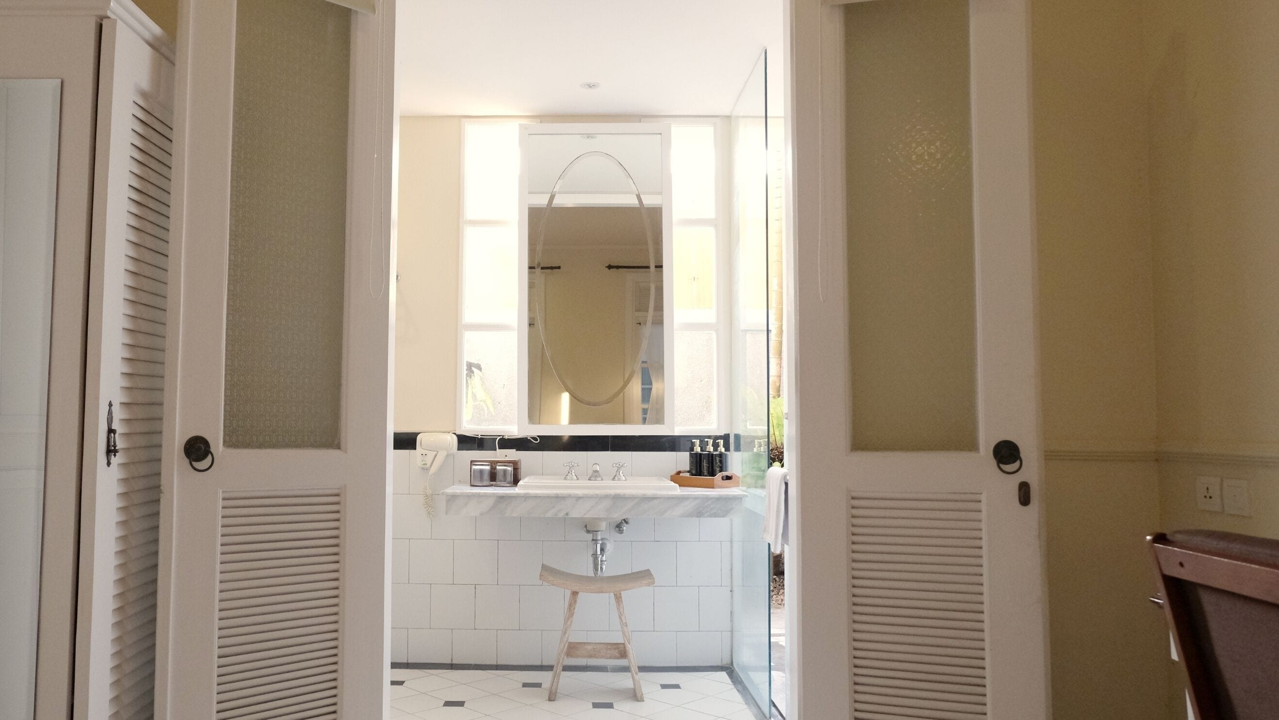 Ein Badezimmer mit Waschbecken, Spiegel und Hockstuhl.