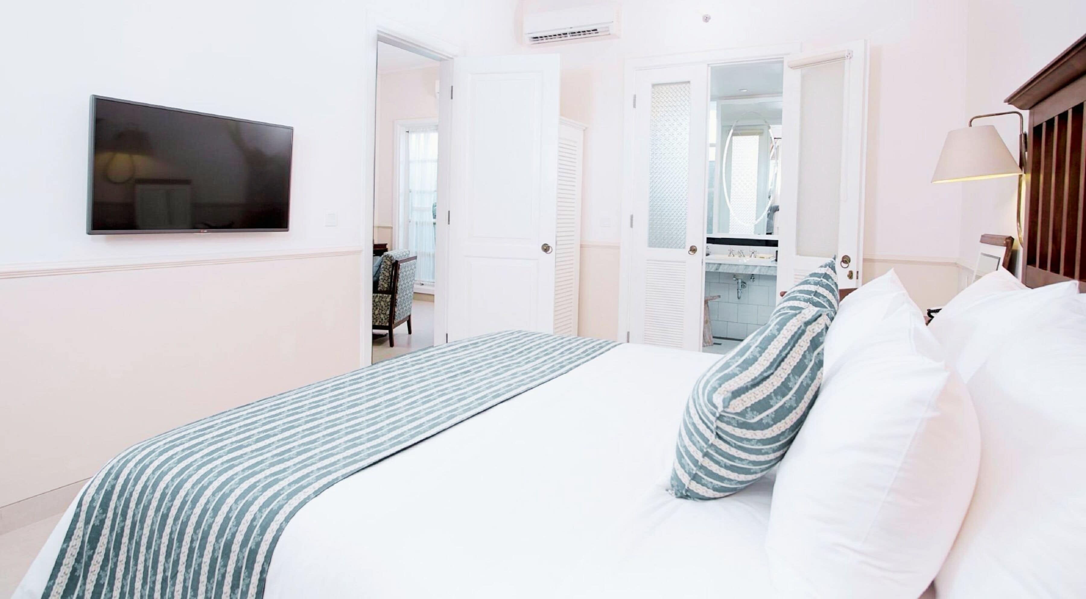 A hotel room with a bed, a TV, and a bathroom visible through an open door.