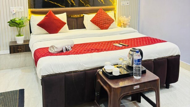 A hotel room with a bed, a bedside table with a bottle, and a wall with a marble-like design. - Vedas Villa (Faizabad)