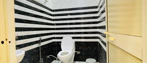 Ein kleines Badezimmer mit Toilette, Waschbecken und einem blauen Eimer.