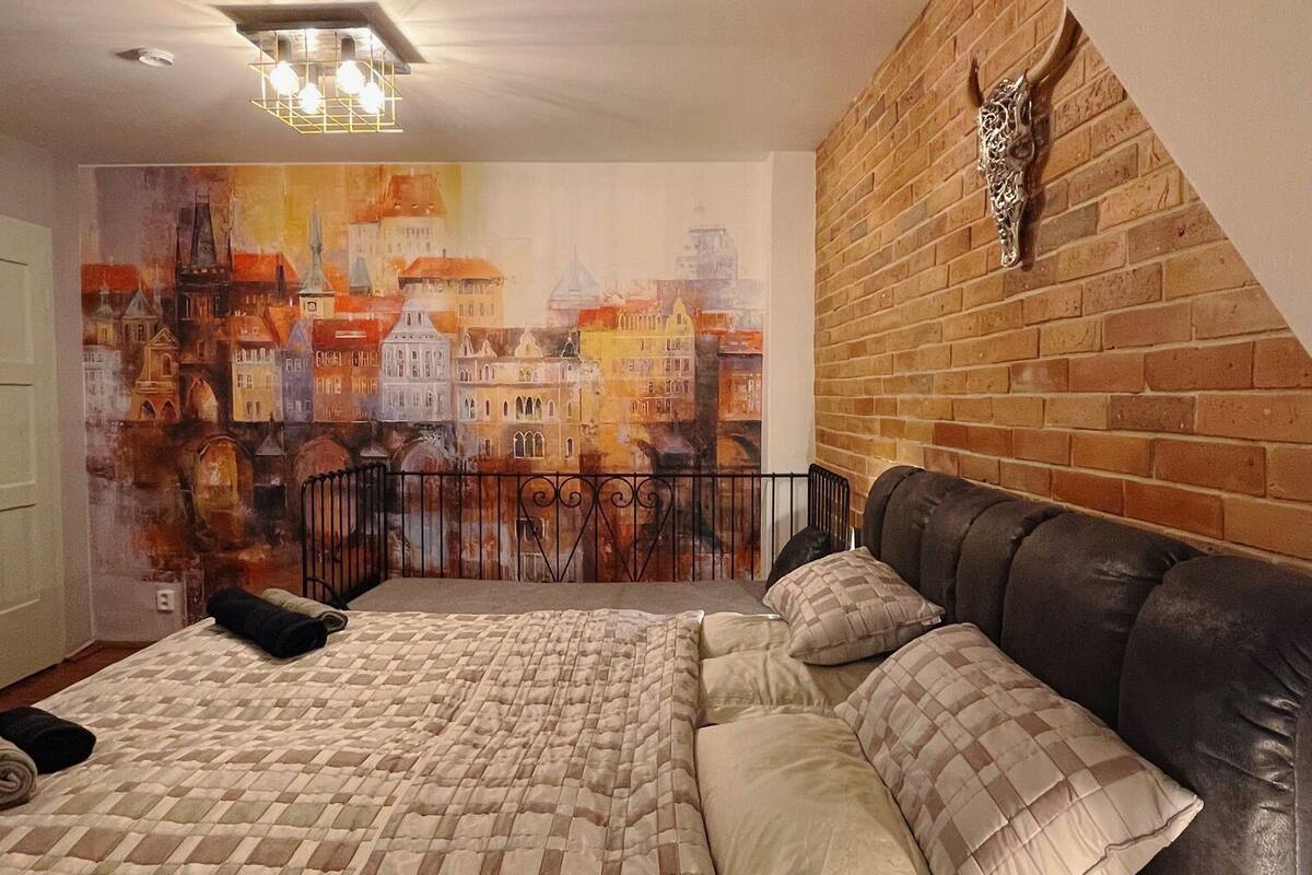 Une chambre à coucher avec un lit, un mur en briques et une fresque représentant un paysage urbain.