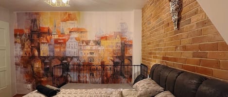 A bedroom with a bed, a brick wall, and a mural of a cityscape.