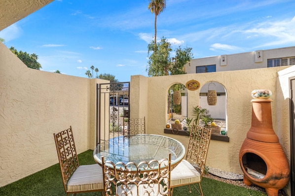 A glass-top table with chairs, a terracotta pot, and a decorative archway.