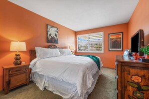 A bedroom with a bed, two bedside tables, a dresser, and artwork on the walls.
