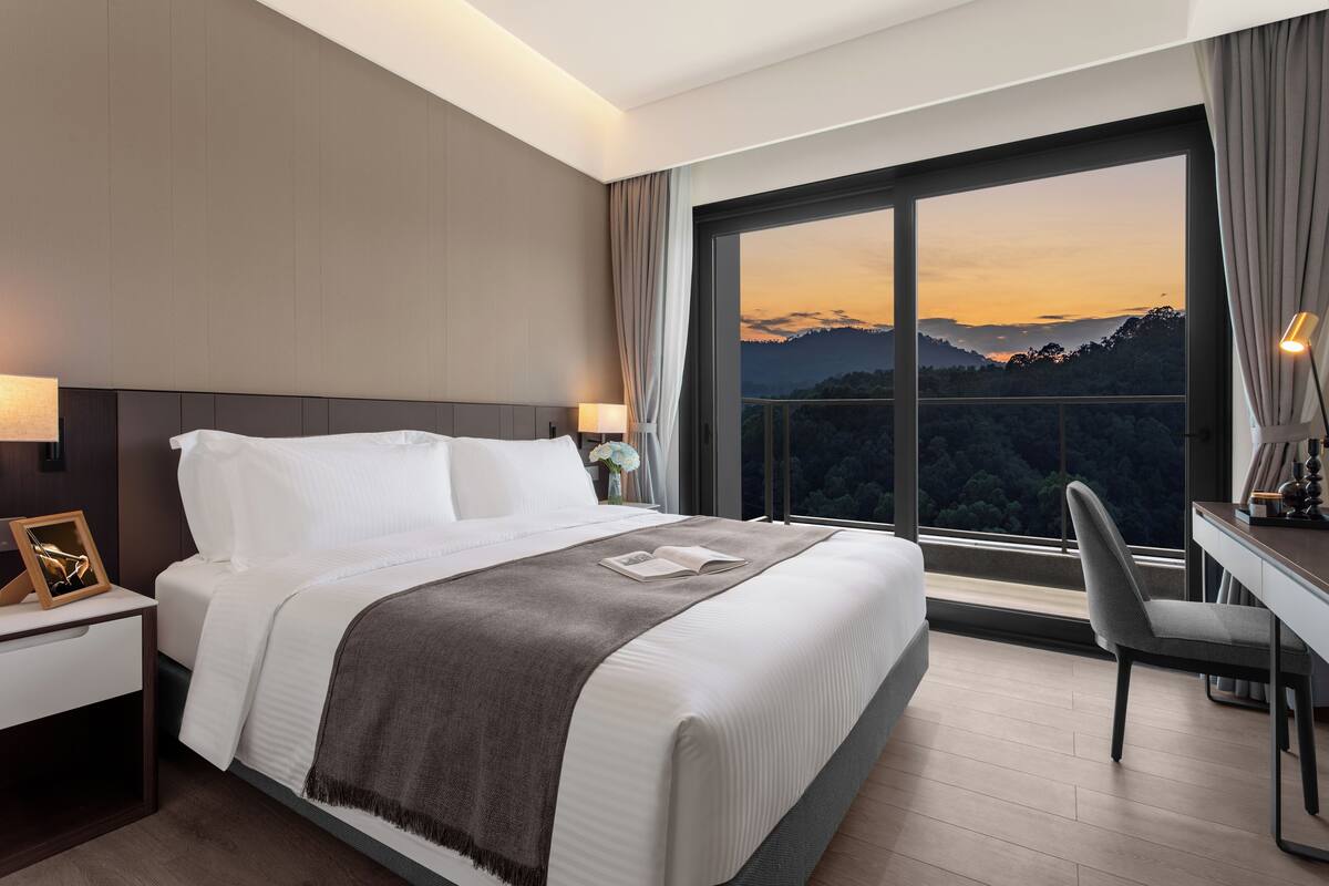 Ein Hotelzimmer mit einem großen Bett, einem Schreibtisch und Blick auf eine Berglandschaft.