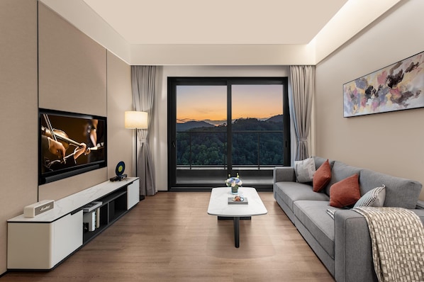 Un salon moderne doté d’un téléviseur à écran plat, d’un canapé, d’une table basse et d’une grande fenêtre offrant une vue panoramique.