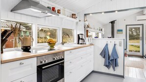 Een moderne keuken met witte kastjes, een roestvrijstalen oven en een groot raam met uitzicht op de omgeving.
