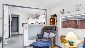 Een gezellige kamer met een rieten stoel, een blauwe deken en een tafeltje met een lamp.