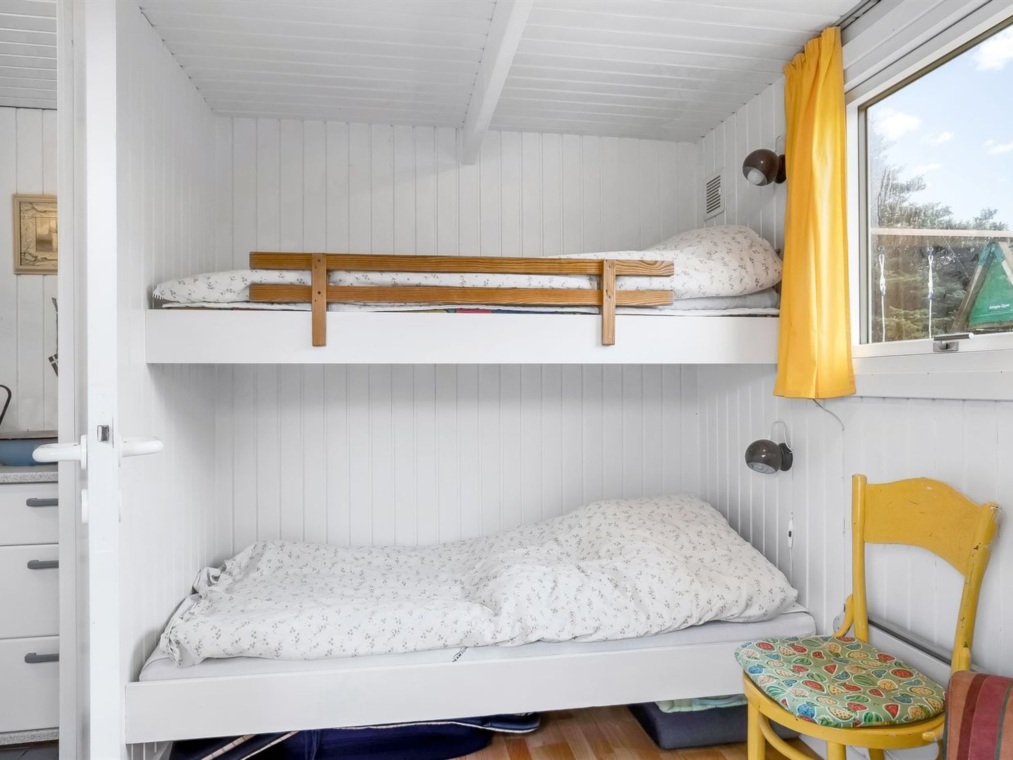 A bunk bed room with a window and a chair.