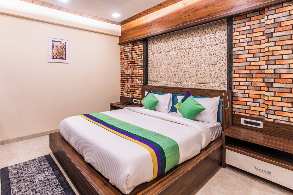 A modern bedroom with a brick-patterned headboard, a wooden nightstand, a bedside table, and a framed picture on the wall.