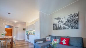 Una sala de estar moderna con un sofá gris, una mesa de centro de madera y una zona de comedor con una mesa y sillas de madera.