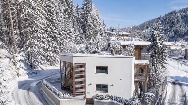 Un edificio moderno con techo plano, un espacio exterior cubierto y un paisaje cubierto de nieve.