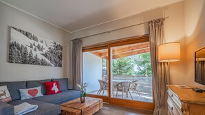 Una sala de estar moderna con un sofá gris, una mesa de centro de madera y un comedor con sillas de mimbre.
