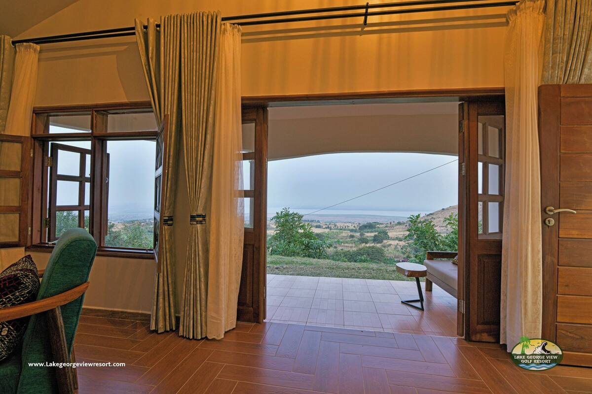 A room with a view of a landscape, a wooden door, and a chair.